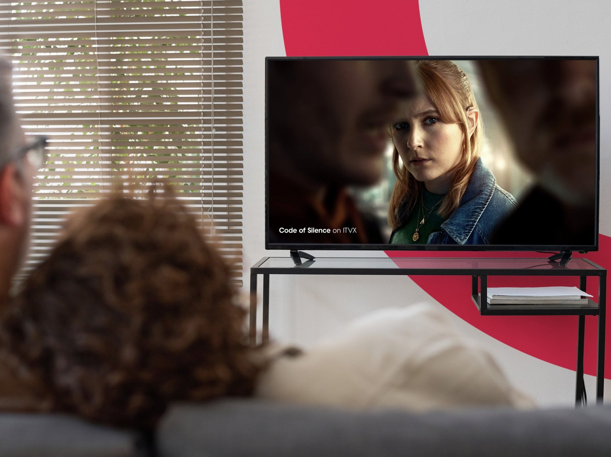 a couple sits on the sofa watching freely on a smart tv