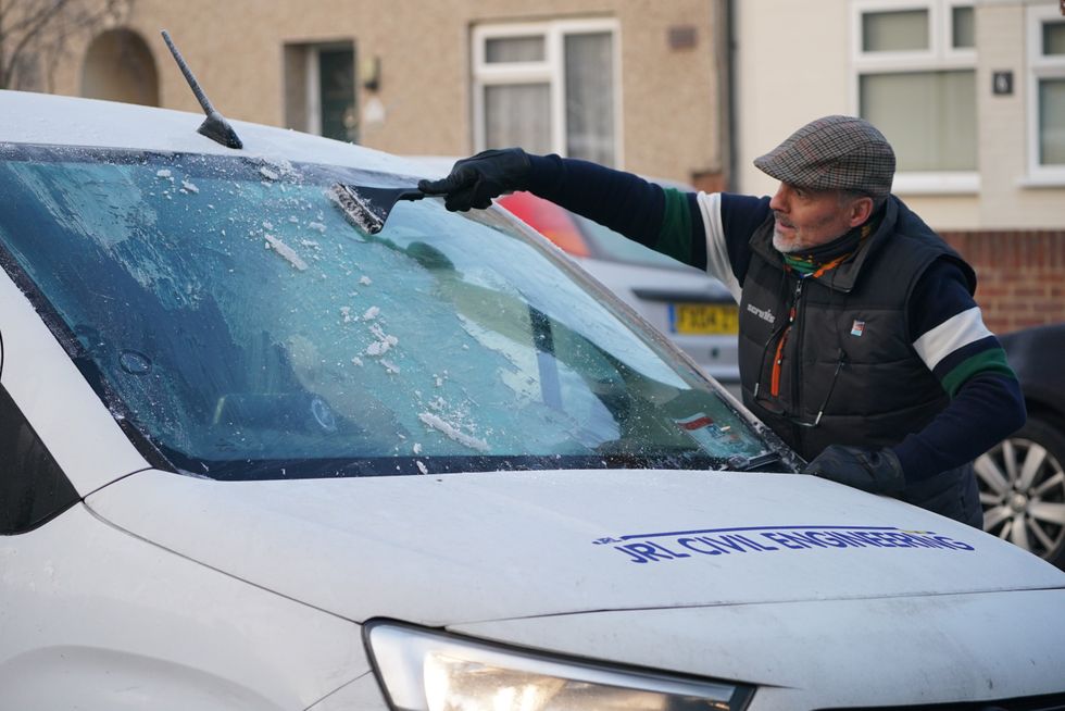 A man clearing windscreen frost