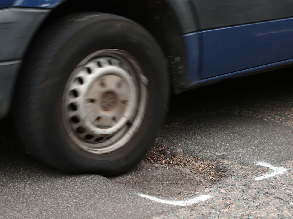 A vehicle driving over a pothole in the road.