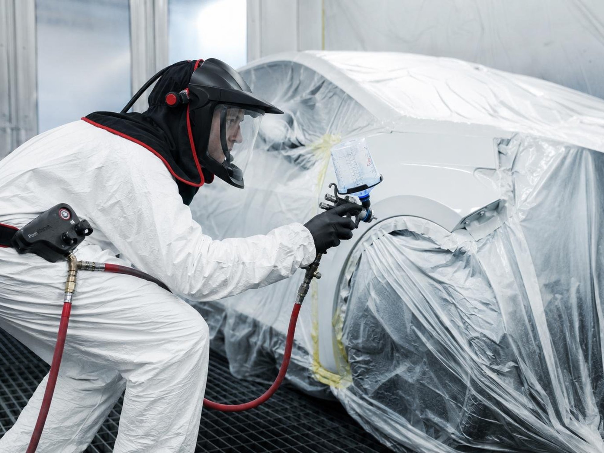 A vehicle paint technician painting a car