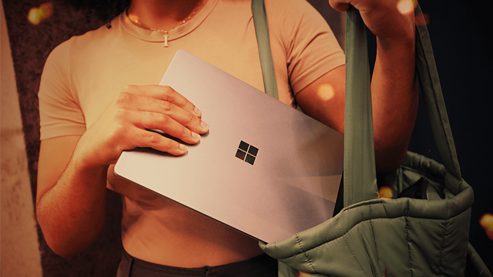 a woman places a surface laptop into her bag with the microsoft logo displayed prominently