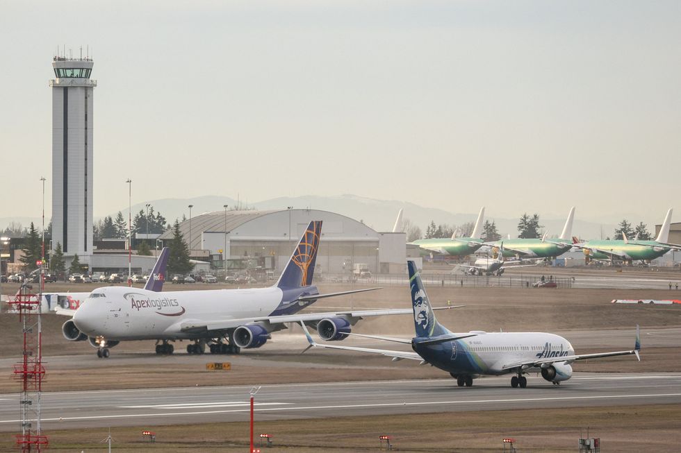 An Alaska Airlines Boeing 737-800 airplane, right, takes off as the final 747 airplane produced by Boeing