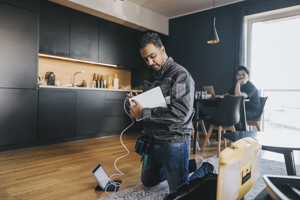 an engineer is pictured wiring a broadband router for a customer in their home