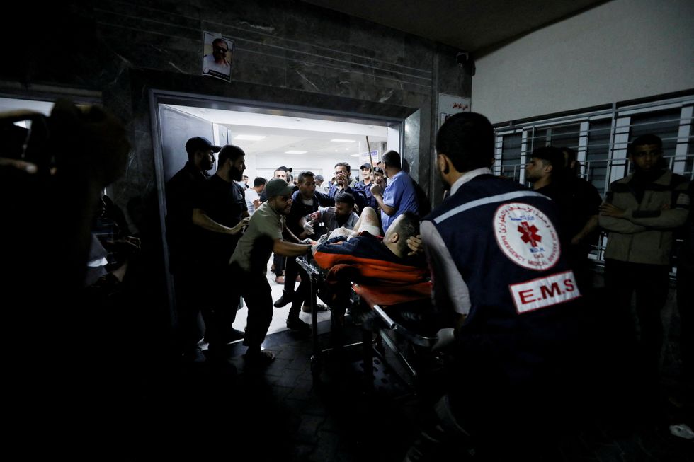 An injured person is assisted at Shifa Hospital after an air strike hit the nearby Al-Ahli Hospital