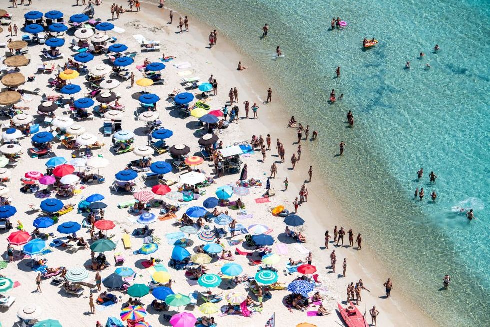 Beachgoers, all with parasols, on Punta Molentis beach