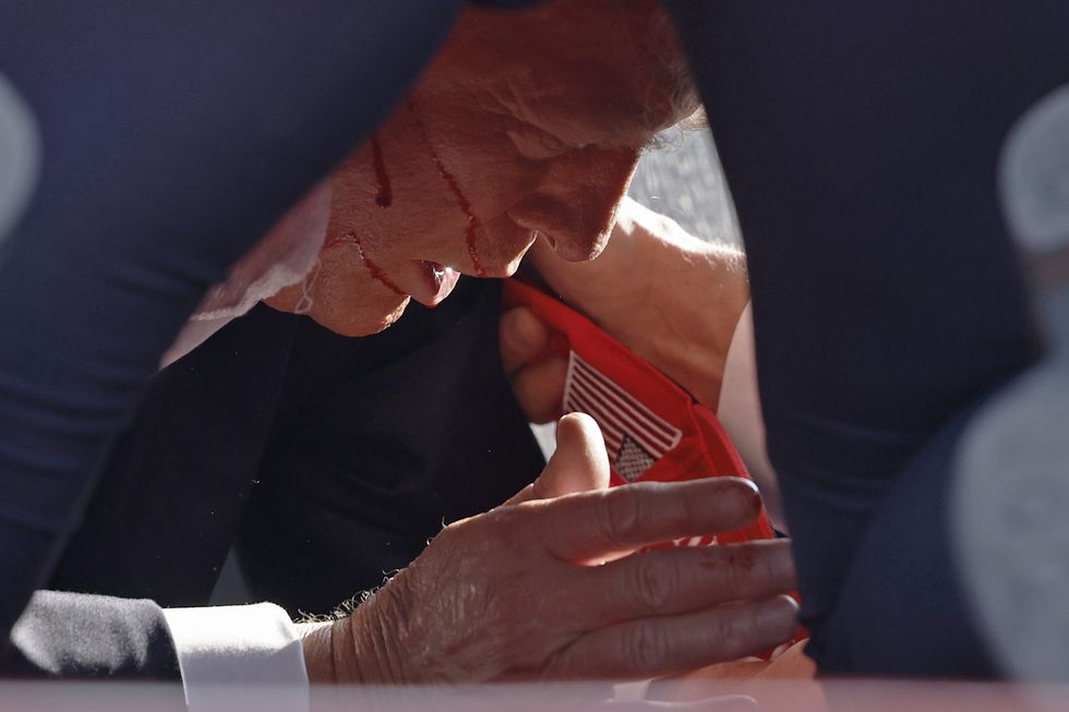 Blood runs down Donald Trump's face after being shot in the ear at campaign rally