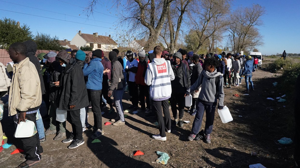 Care4Calais worker and queue of illegal migrants