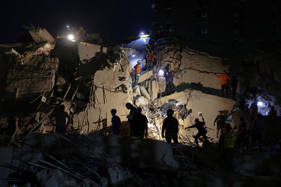 Emergency services work at the site of a collapsed building after last night's earthquake, in Caracas