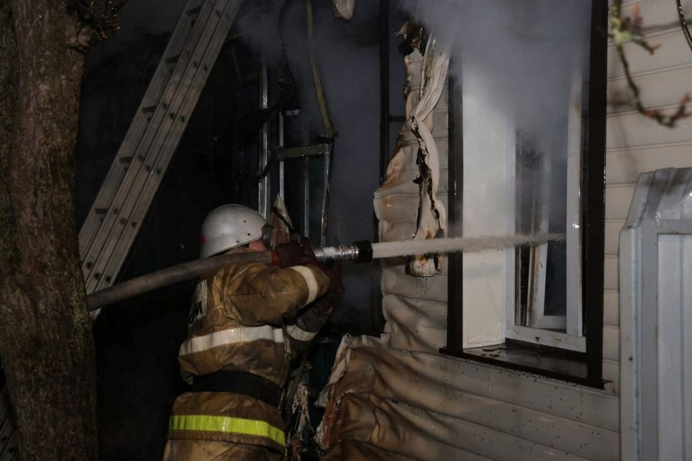 Firefighters work to extinguish a fire after air defences downed an alleged Ukrainian drone, in Kursk
