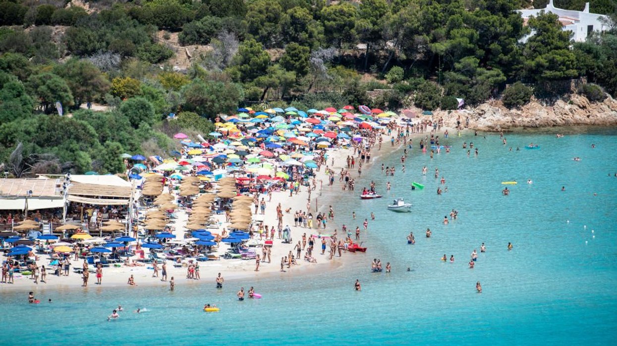 Hundreds of beachgoers with parasols on Punta Molentis beach