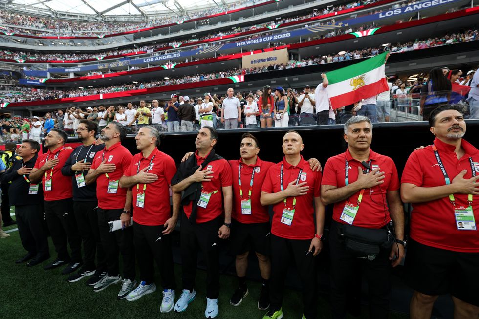 Iran staff embrace for the national anthem prior to their World Cup clash with New Zealand