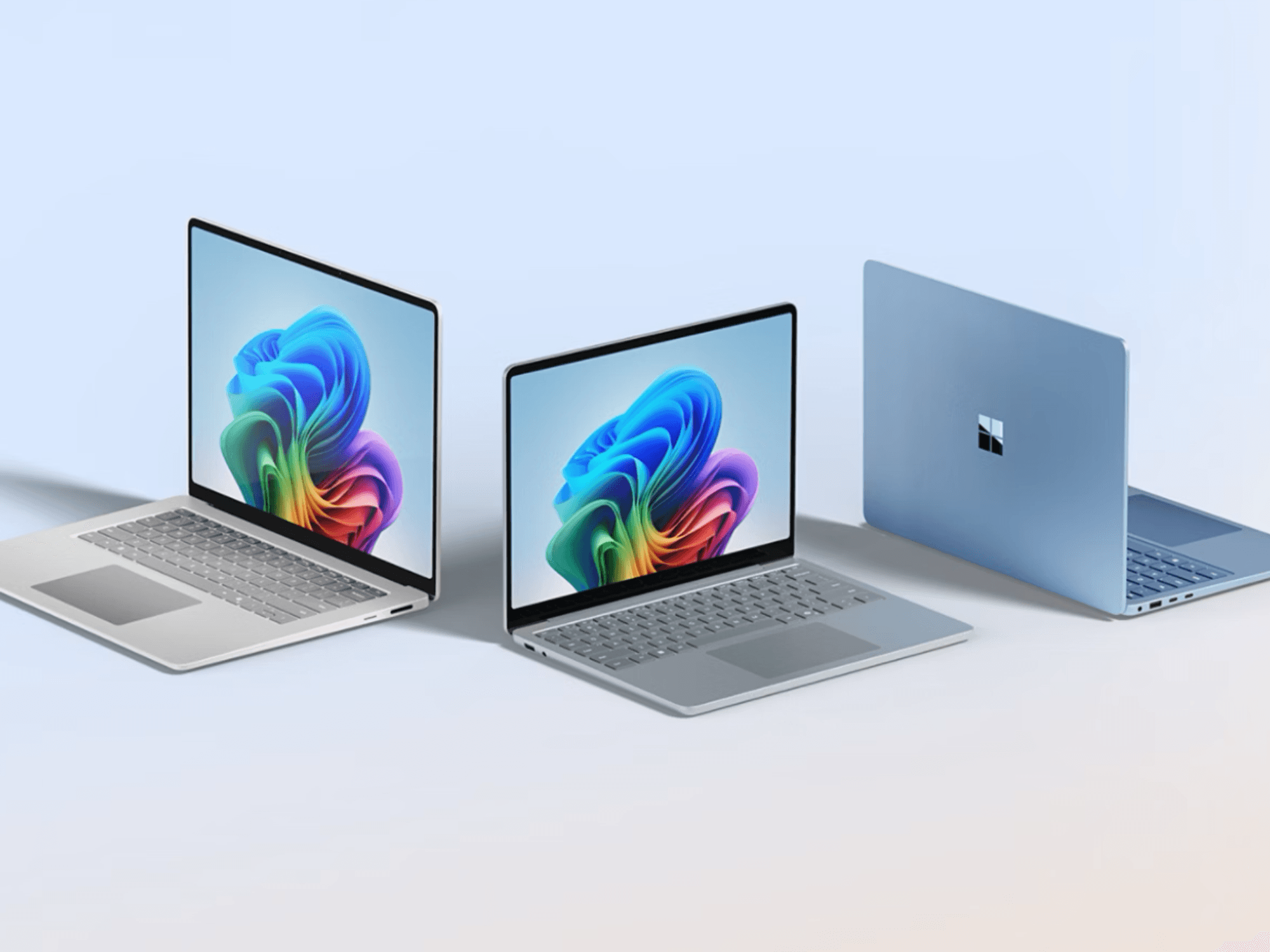 laptops running windows 11 pictured side by side on a plain background