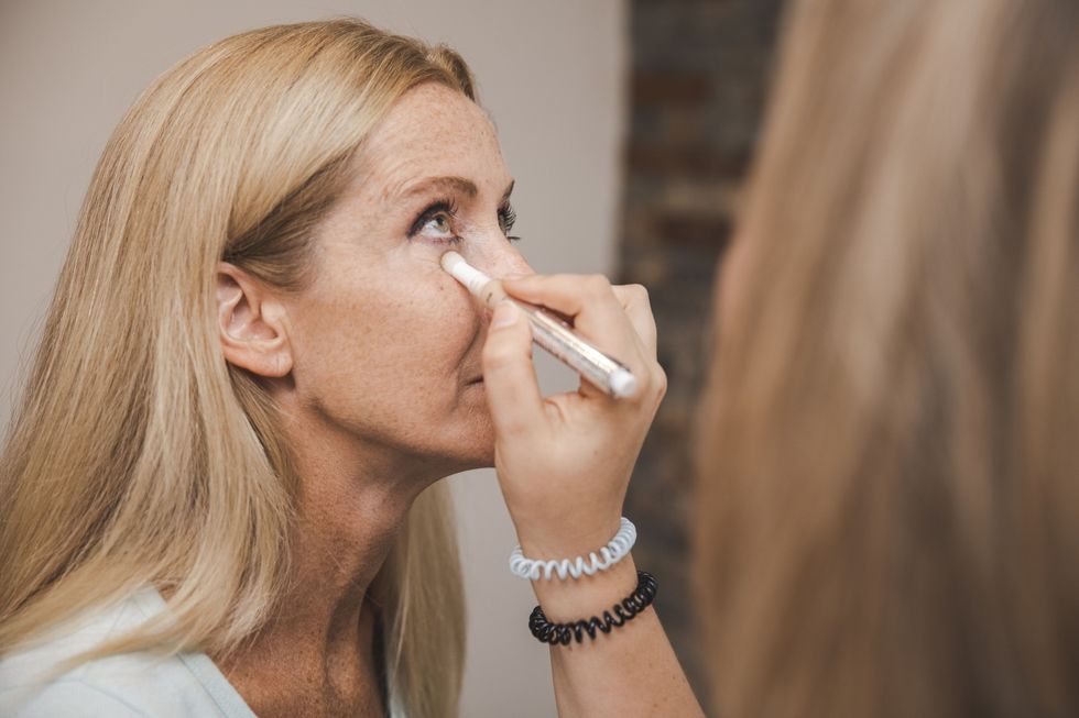 Makeup artist applying concealer to woman's face