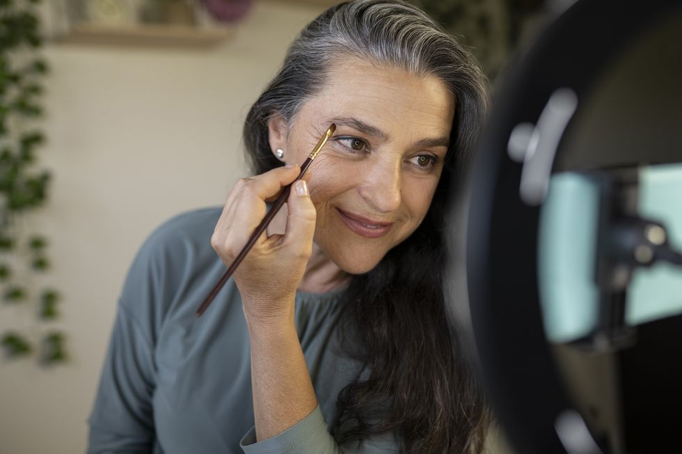 Mature woman doing her eyebrows