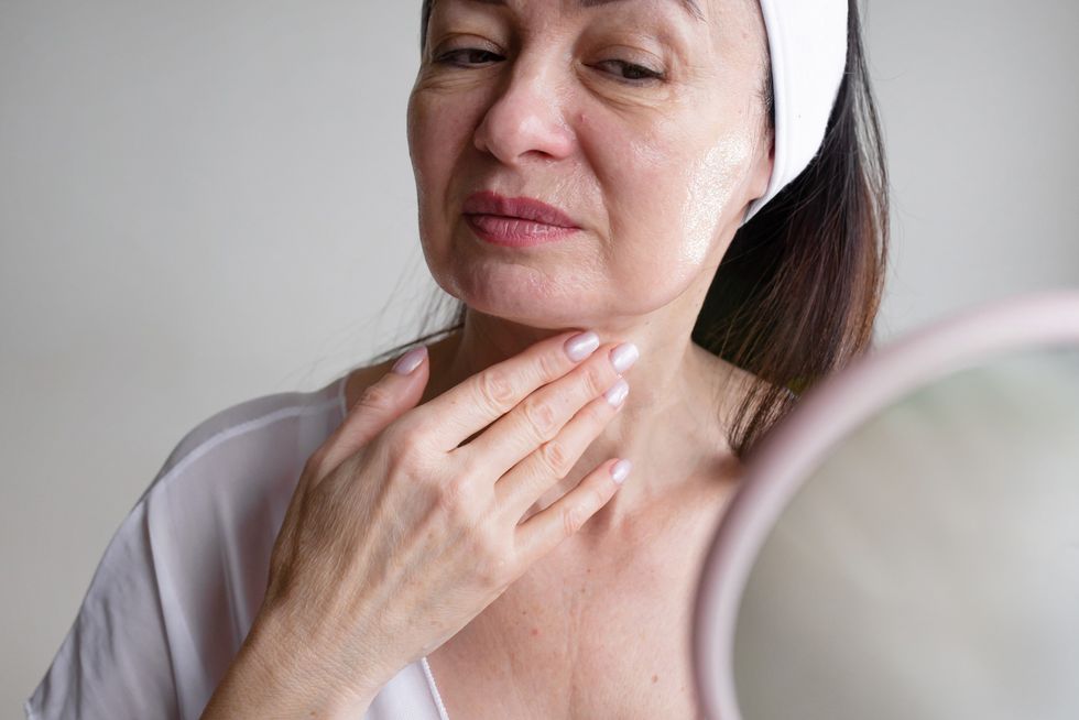 Mature woman looking at her face in mirror