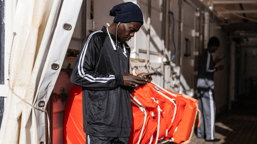 Migrant using phone onboard the rescue ship 'Ocean Viking'