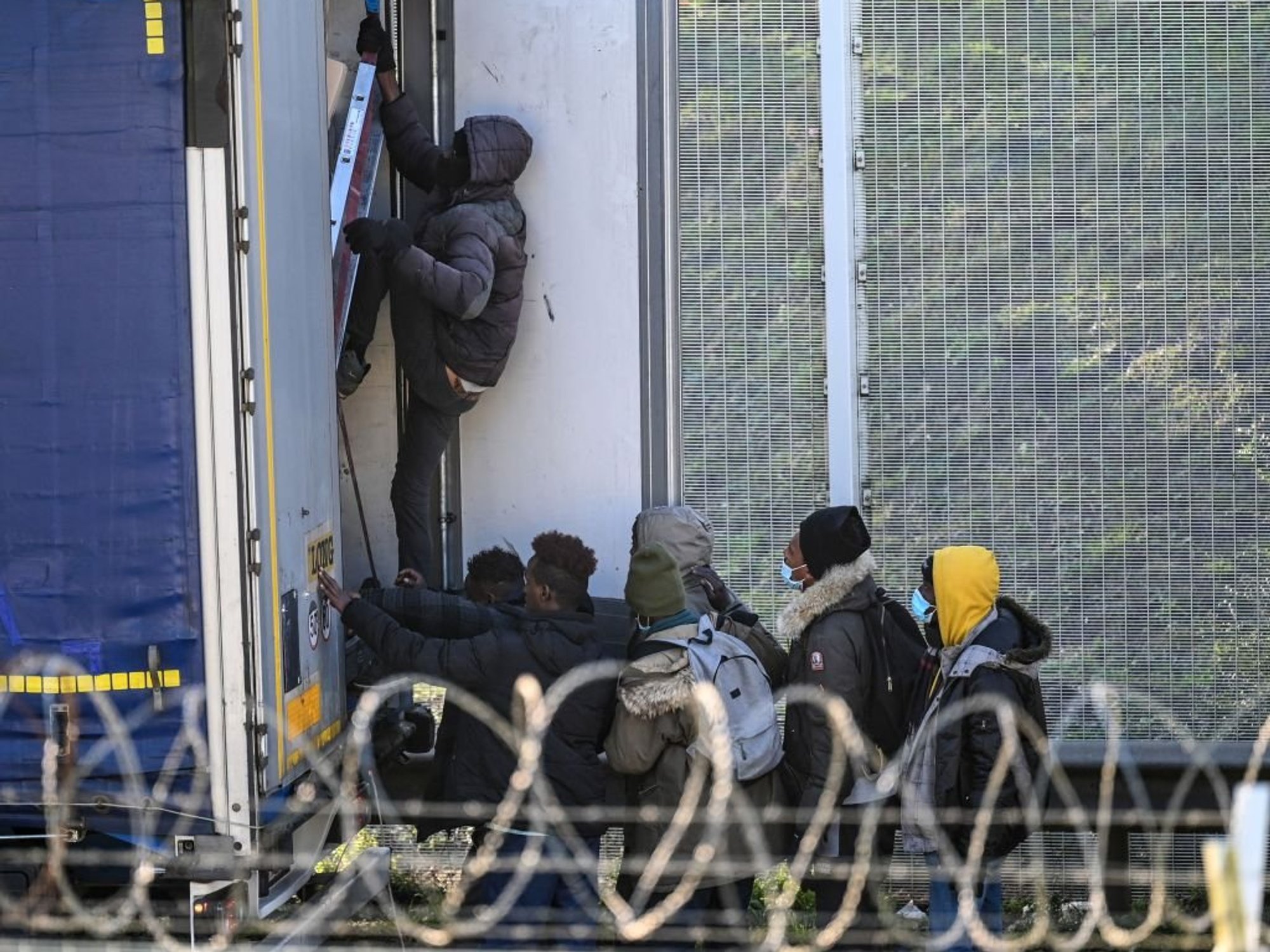 Migrants climb into the back of lorries bound for Britain