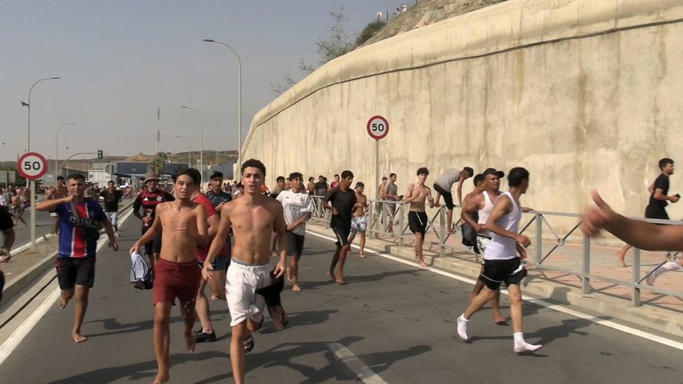 Migrants running on the roads of Ceuta after swimming from Morocco