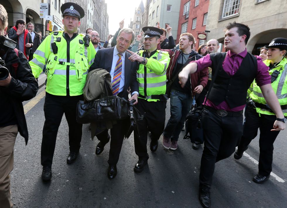 Nigel Farage is escorted by police officers as he leaves the Cannons Gait pub as protestors heckle him