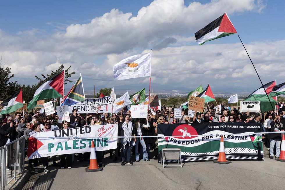 Peace protesters wave Palestinian flags in front of the gates of the Royal Air Force Akrotiri base, a British overseas territory near the Cypriot coastal city of Limassol