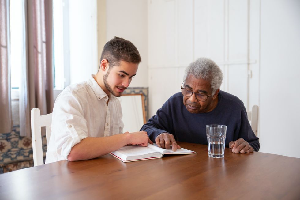 Pensioner and younger person looking at book