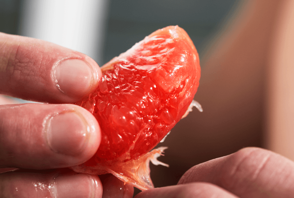 Person holding a slice of grapefruit