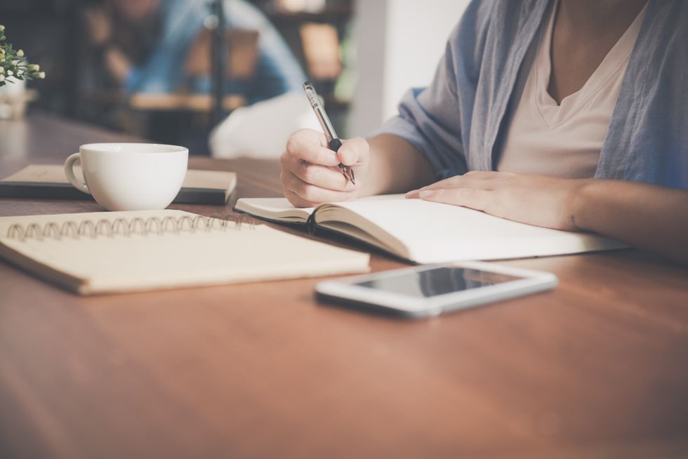Person looking at notebook and phone