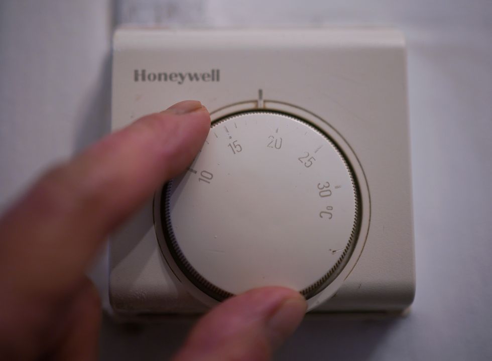 Person turns up dial on thermostat