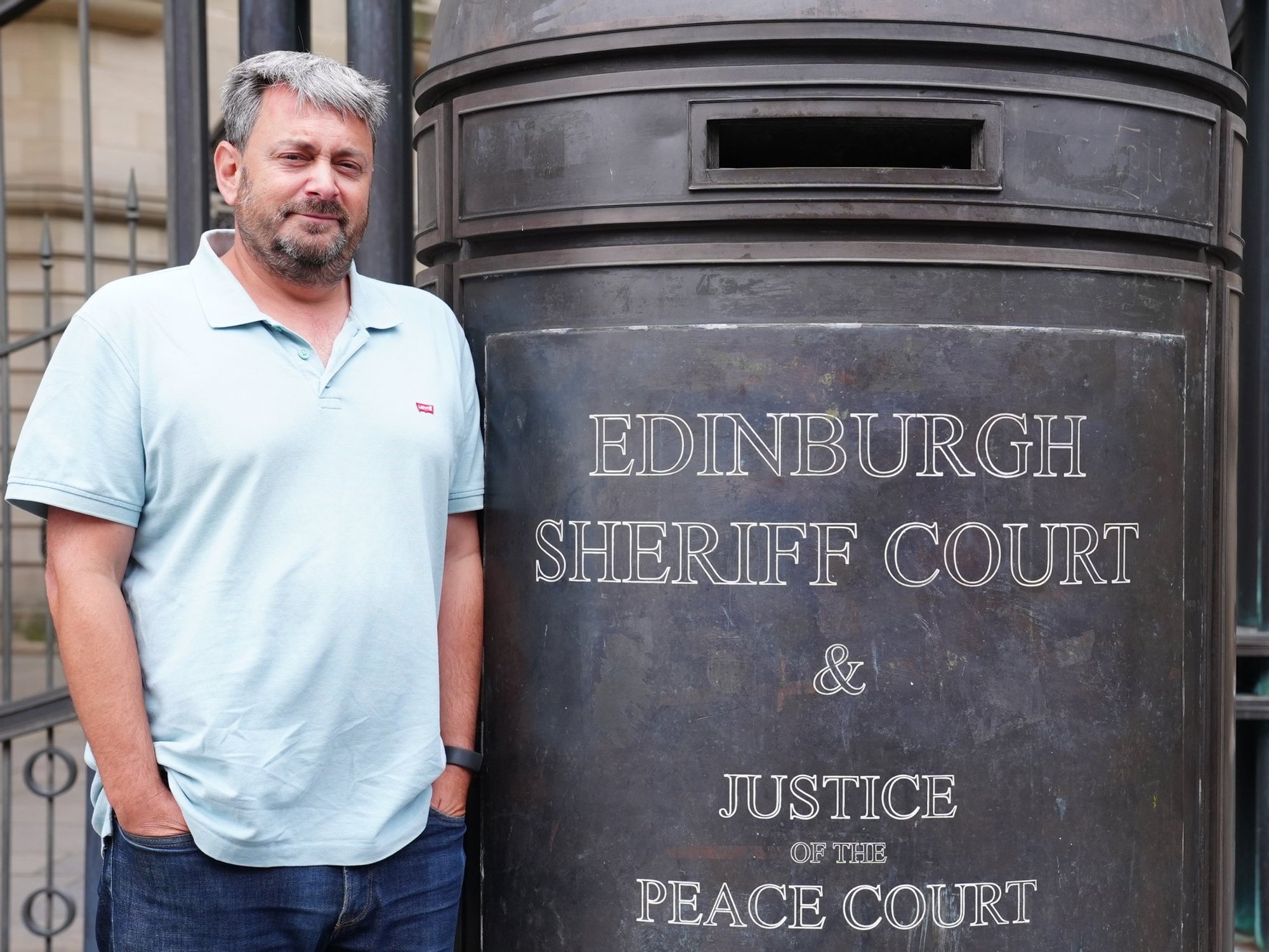 Philip Simon standing by sign for Edinburgh Sheriff Court