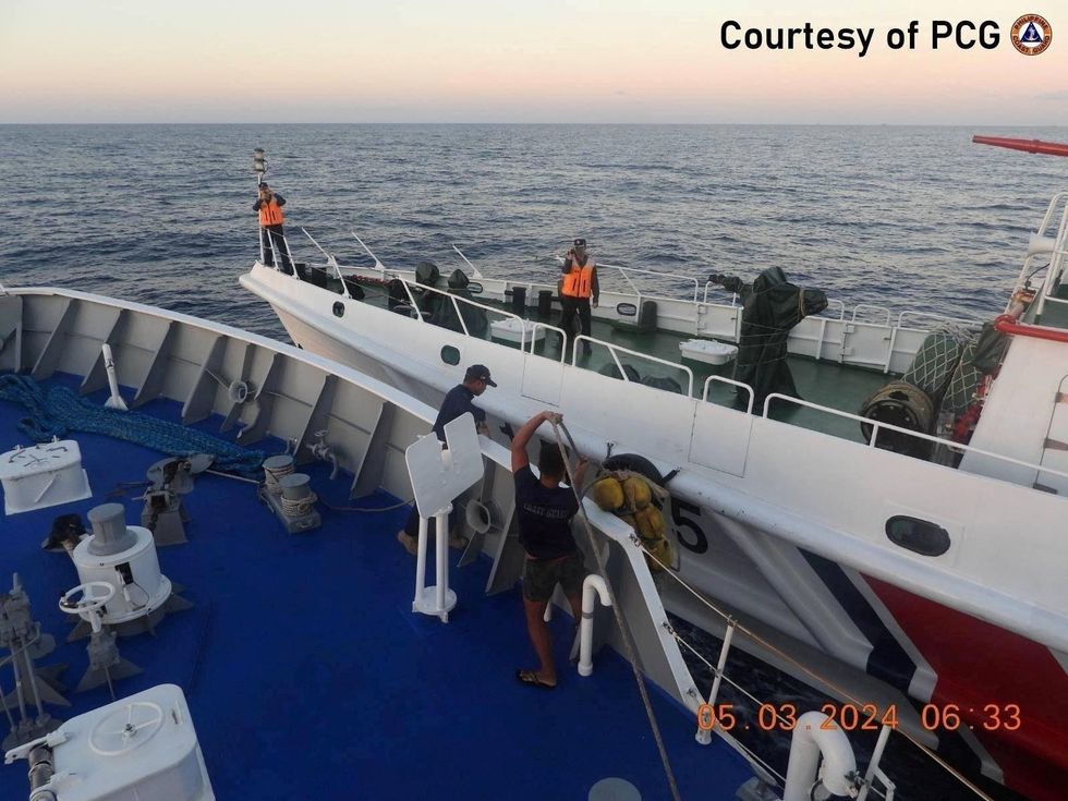 Philippine Coast Guard personnel inspect the hull of the ship during a collision incident