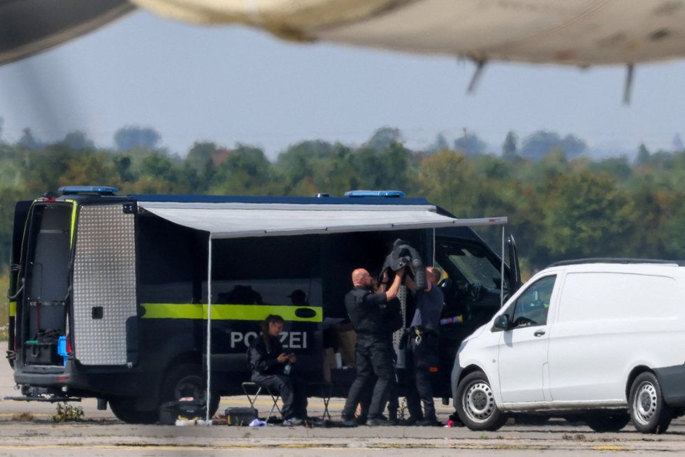 Police gear up a bomb-disposal expert as he prepares to enter the runway