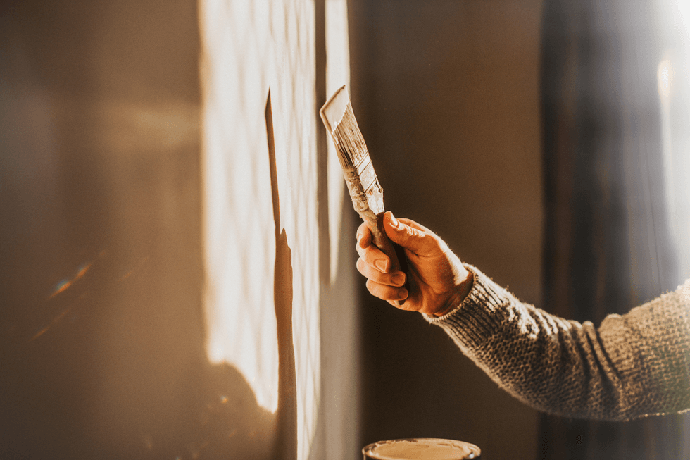 Someone using a brush to paint a wall