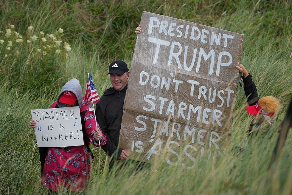 Supporter of Trump holding signs telling him not to trust Starmer