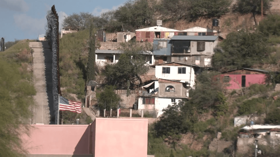 The Stars and Stripes fly by the US-Mexico border wall in Arizona