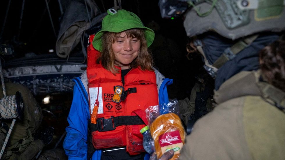 \u200bAn Israeli solider passes a bun to Greta Thunberg onboard the Gaza-bound British-flagged yacht "Madleen"