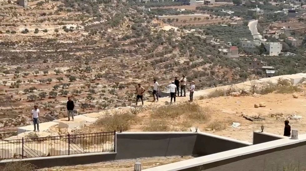\u200bIsraeli settlers gather outside a Palestinian home
