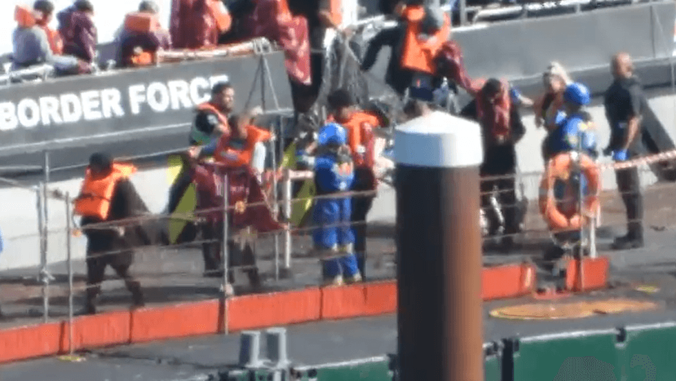 \u200bMigrants are seen wrapping themselves in blankets after arriving in Dover