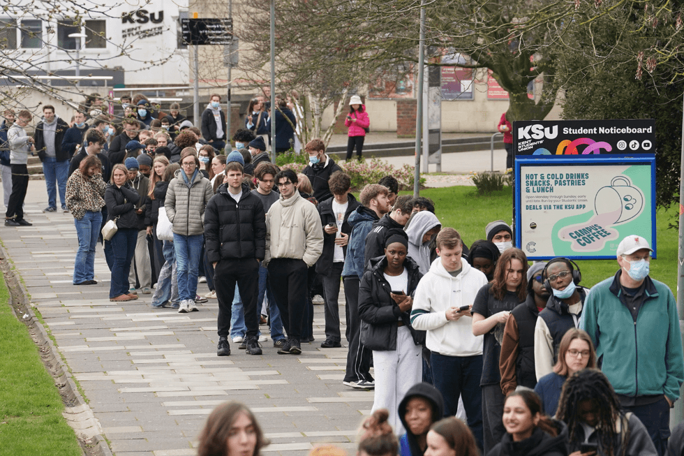 \u200bStudents queuing for antibiotics outside a building