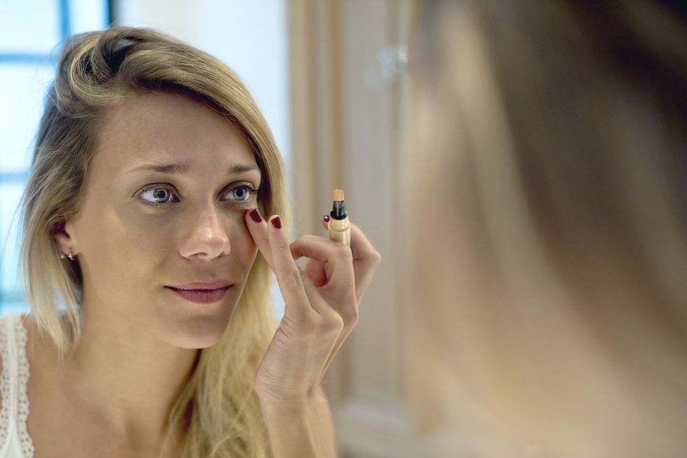 Woman applying concealer underneath her eyes