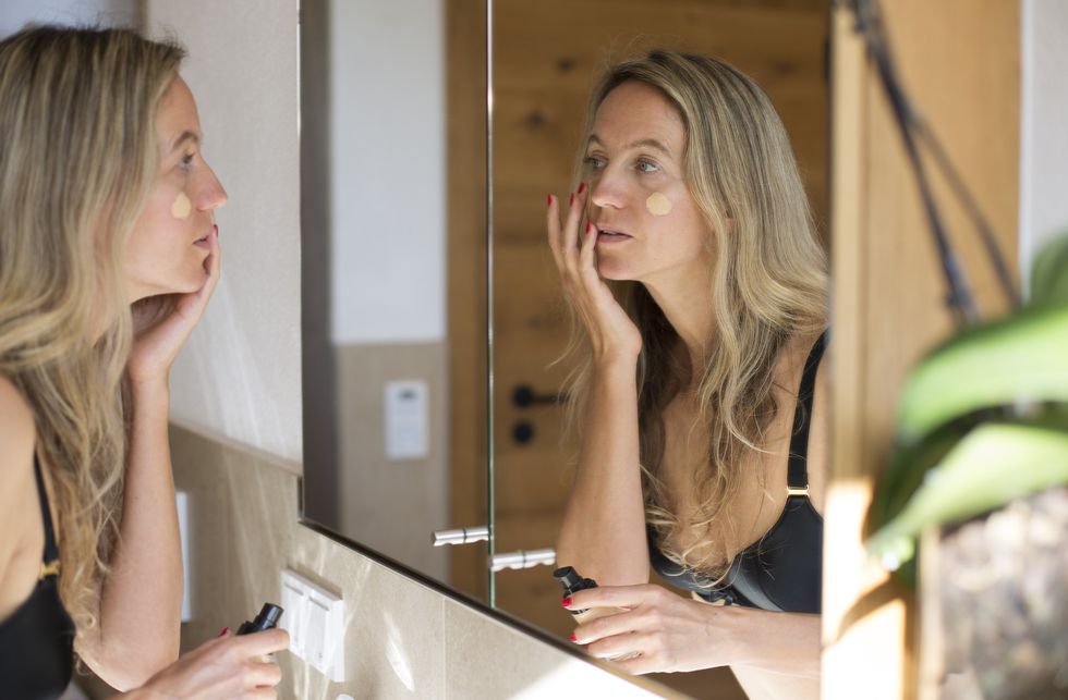 Woman applying foundation on her face