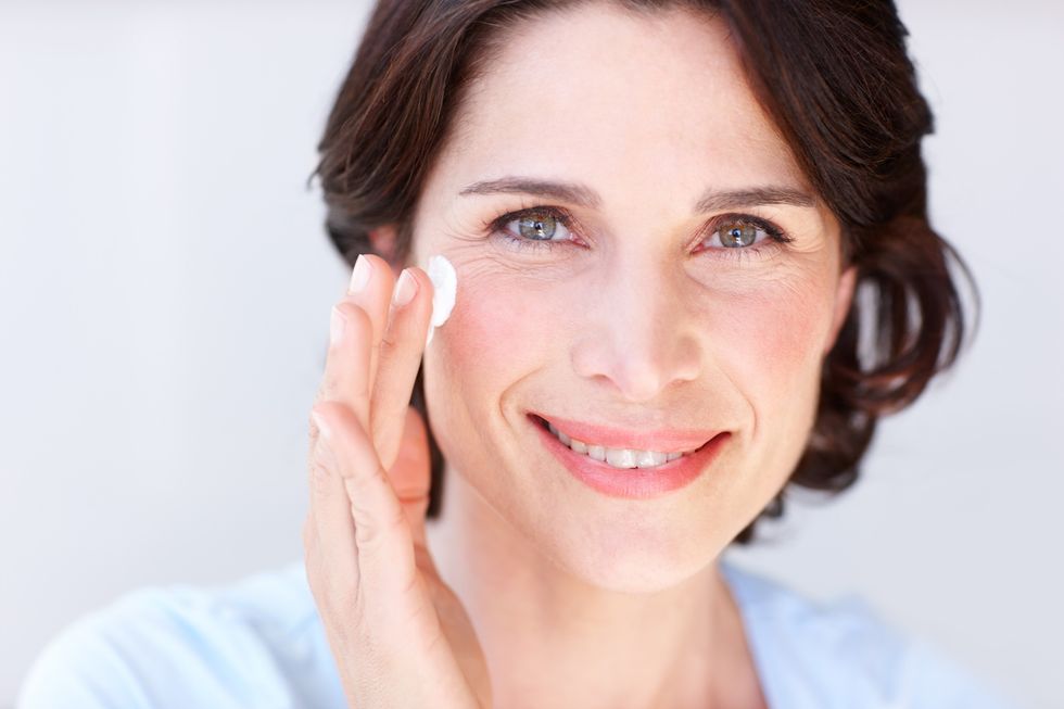 Woman applying moisturiser / sunscreen to her face