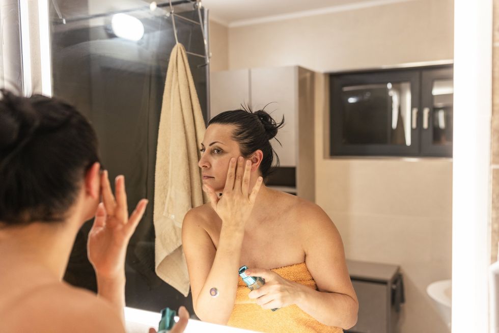 Woman applying primer to her face