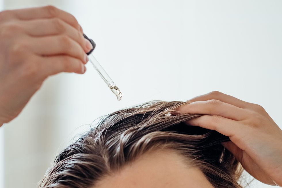 Woman dropping oil onto hair