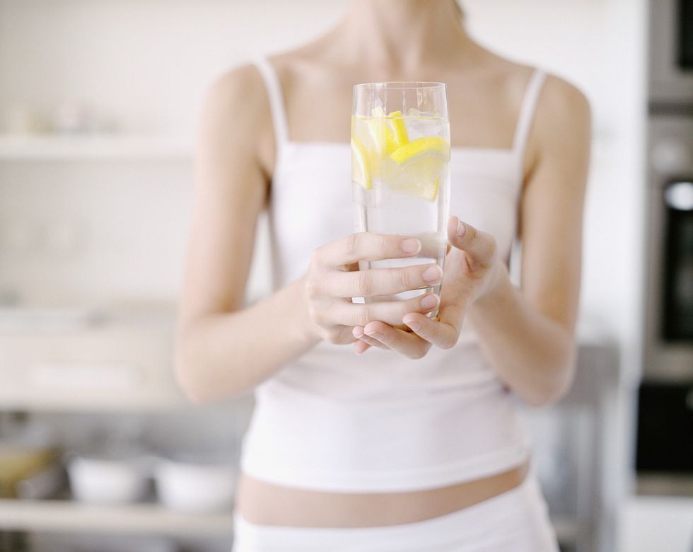 Woman holding a glass of water and lemon