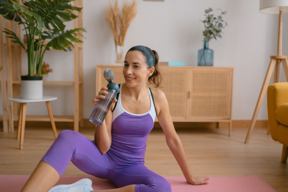 Woman in gym gear drinking water bottle