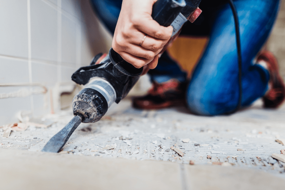 Woman removing old tiles, renovating the bathroom