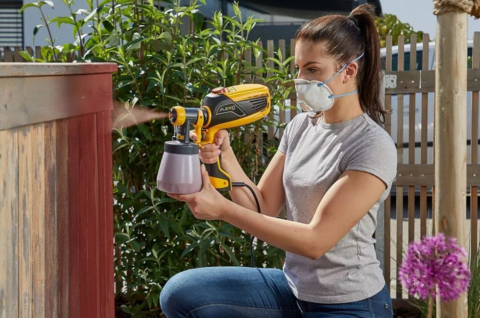 Woman spray painting a fence